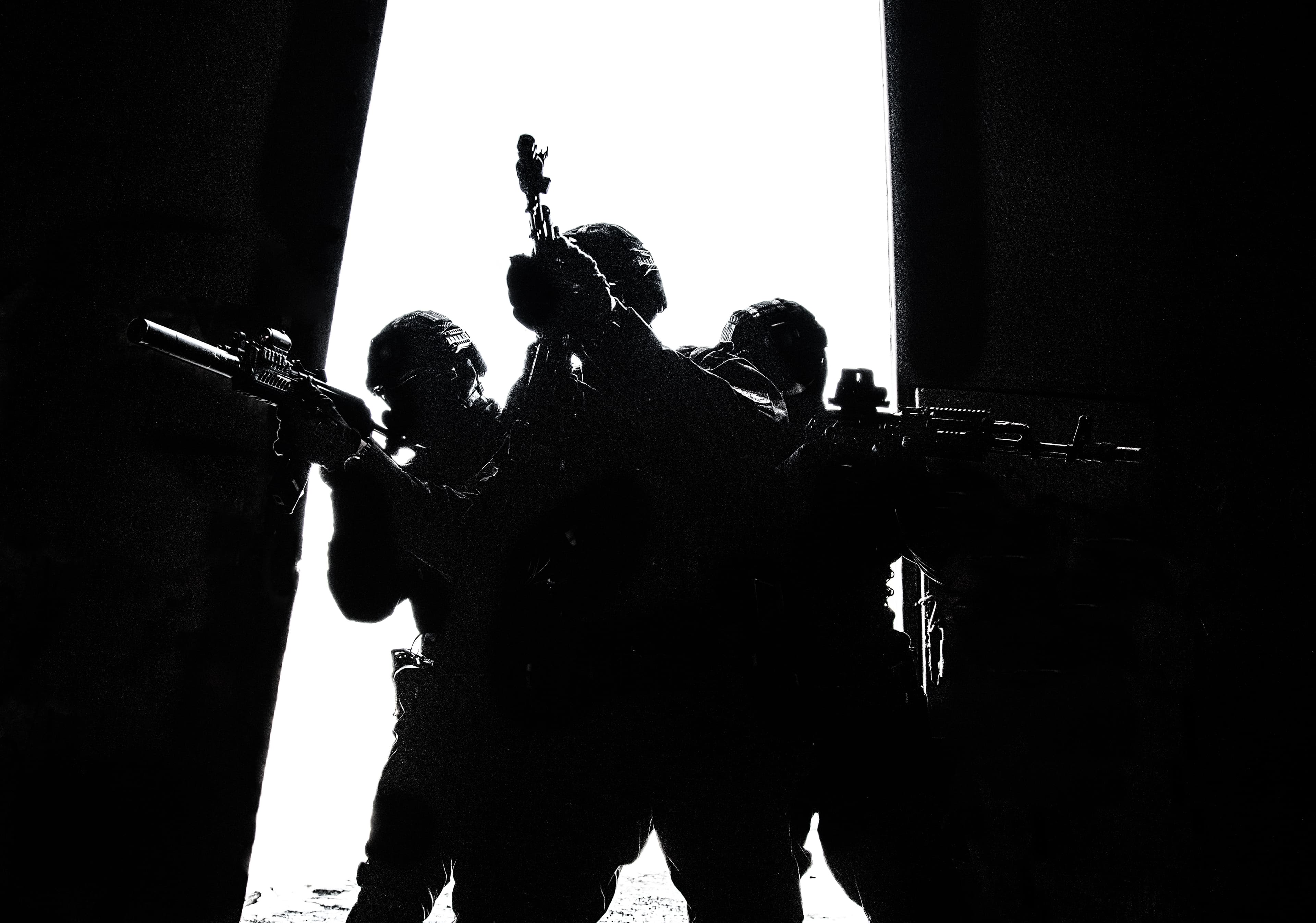 The silhouette of three operators breaching a doorway.